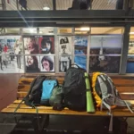 backpacks lying on a bench below pictures of the Beatles in the bus terminal of posadas, argentina