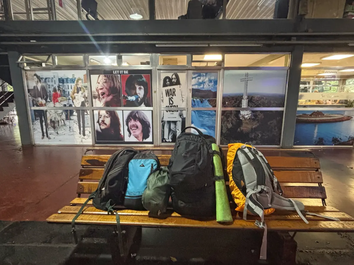 backpacks lying on a bench below pictures of the Beatles in the bus terminal of posadas, argentina