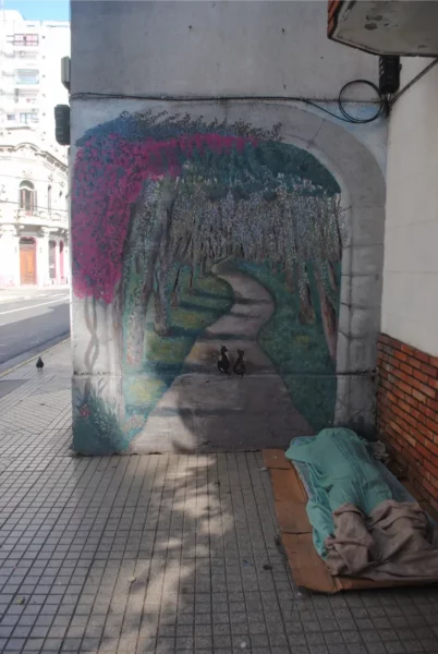 Vibrant mural depicting a wooded path, with shades of pink and green, alongside a quiet street in Rosario, Santa Fe, Argentina.