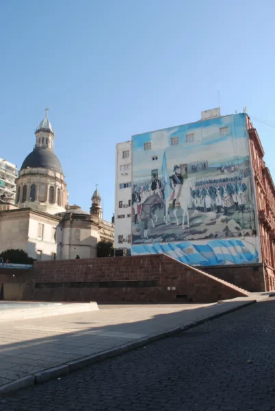 Vibrant mural alongside historic architecture under a clear blue sky in Rosario, Santa Fe, Argentina.