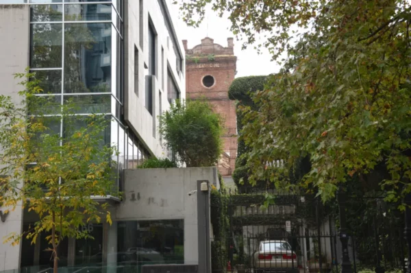 Modern architecture blends with lush greenery and a historic tower in Rosario, Santa Fe, Argentina.