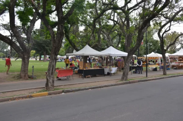 Vibrant market stalls under leafy trees in Rosario, Santa Fe, Argentina, showcasing local crafts and foods.