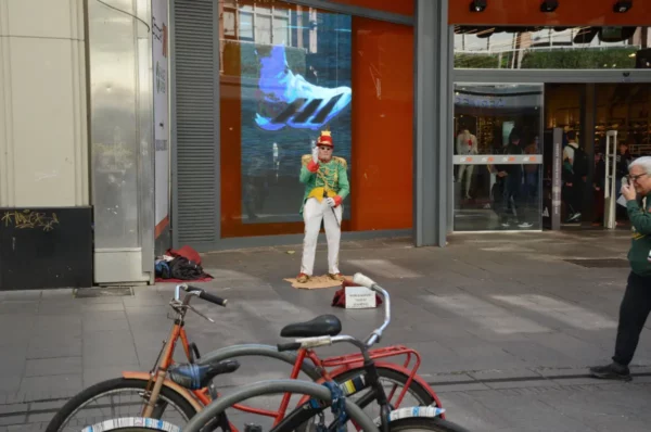 Street performer in vibrant attire near a store front, with bicycles parked in the foreground, Rosario, Santa Fe, Argentina.