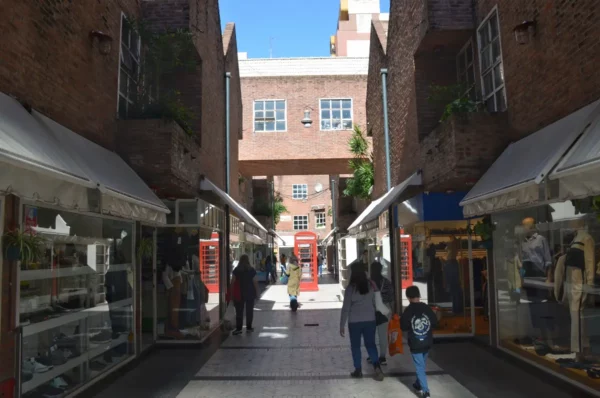 Charming alleyway in Rosario, Santa Fe, Argentina, featuring stylish shops, green plants, and bright blue skies.