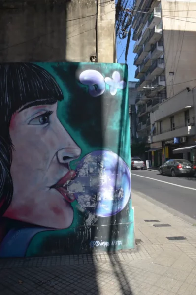 Colorful mural featuring a woman's profile blowing a bubble in Rosario, Santa Fe, Argentina, showcasing vibrant street art.