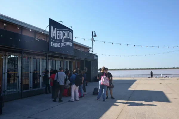 People gather outside Mercado de Productos Culturales along the riverbank in Rosario, Santa Fe, Argentina, under string lights.