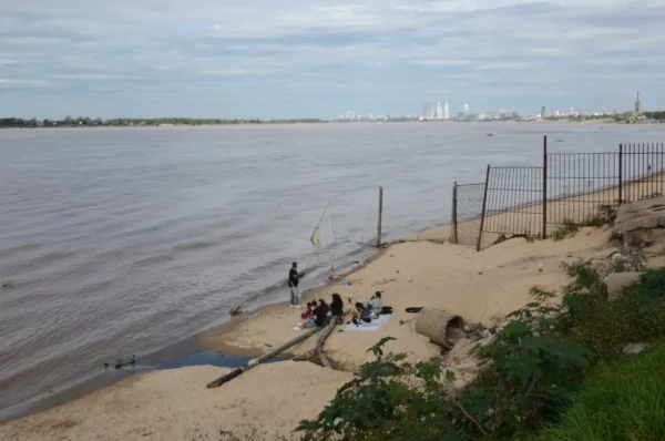 Fishing along the sandy shores of the Paraná River in Rosario, Santa Fe, Argentina, with a city skyline in the background.