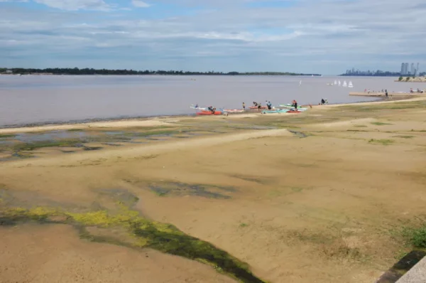 Lush riverbanks with sandy shores and people kayaking along the Paraná River in Rosario, Santa Fe, Argentina.