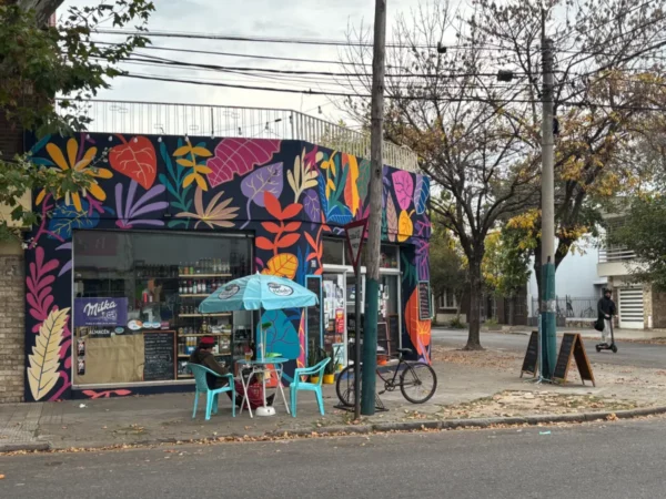 Colorful mural-covered shopfront with vibrant floral designs, featuring turquoise seating and a bicycle outside in Rosario, Santa Fe, Argentina.