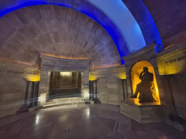 Elegant statue illuminated in a circular chamber, featuring warm tones and blue lighting, located in Rosario, Santa Fe, Argentina.