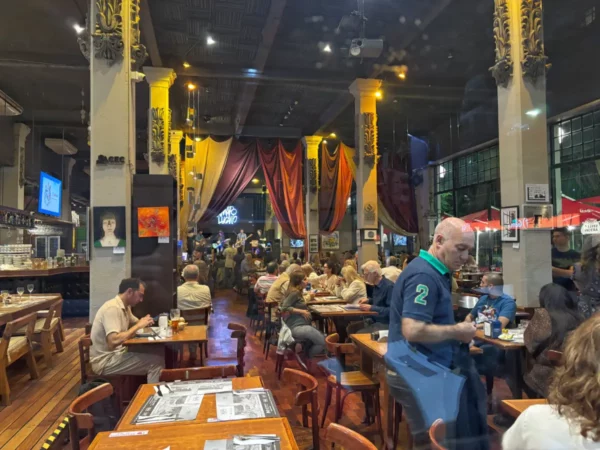 Vibrant interior of a busy café in Rosario, Santa Fe, Argentina, featuring patrons enjoying meals amid warm lighting and decor.