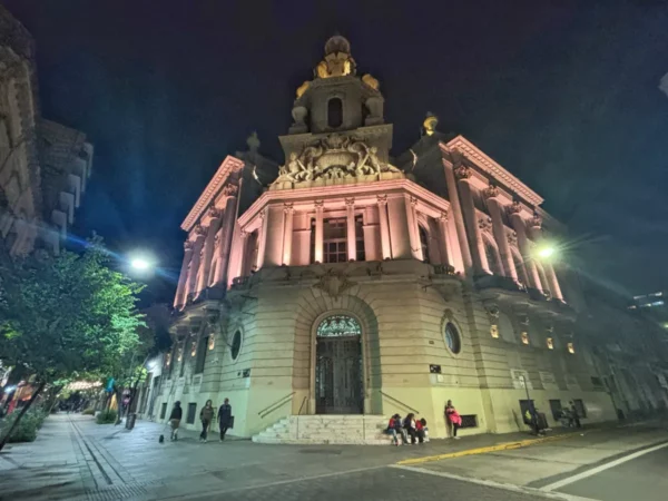 Historic architecture illuminated at night showcases intricate details in Rosario, Santa Fe, Argentina, with lively street ambiance.