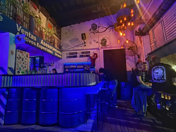 Vibrant bar scene with blue lighting and decorative murals in Rosario, Santa Fe, Argentina, showcasing a lively atmosphere.
