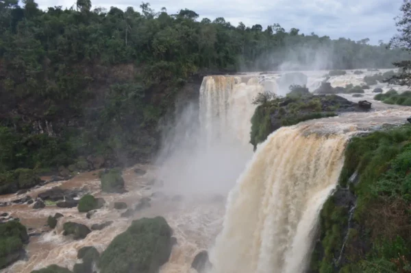 Majestic cascading waterfalls at Saltos del Monday in Paraguay, surrounded by lush greenery and misty atmosphere.