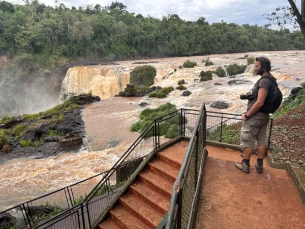 Stunning view of Saltos del Monday Falls with lush greenery and cascades, as a visitor admires the breathtaking scenery in Paraguay.