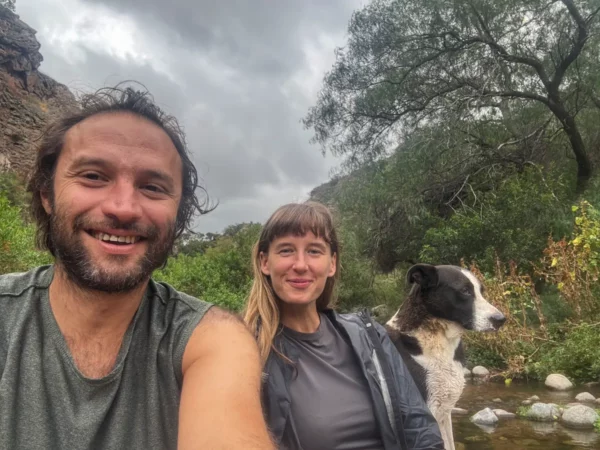 Couple and dog by river in the hippie village of san marcos sierras in cordoba, argentina