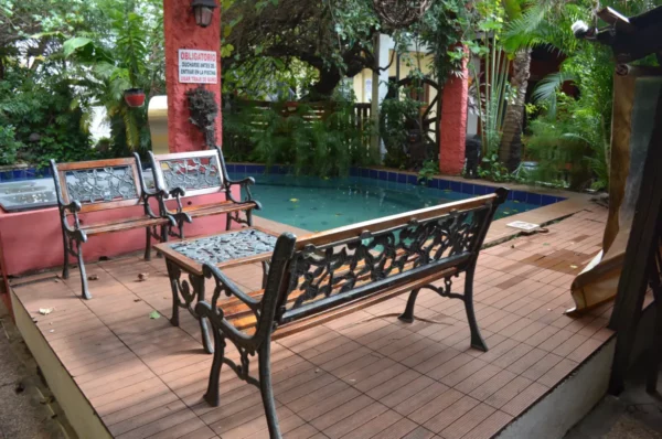 Relaxing patio with ornate benches surrounding a small pool, lush green foliage providing a tranquil atmosphere in Villarica, Paraguay.