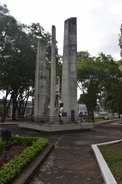 Villarica's monument stands among greenery, featuring tall concrete pillars surrounded by a well-maintained park setting.