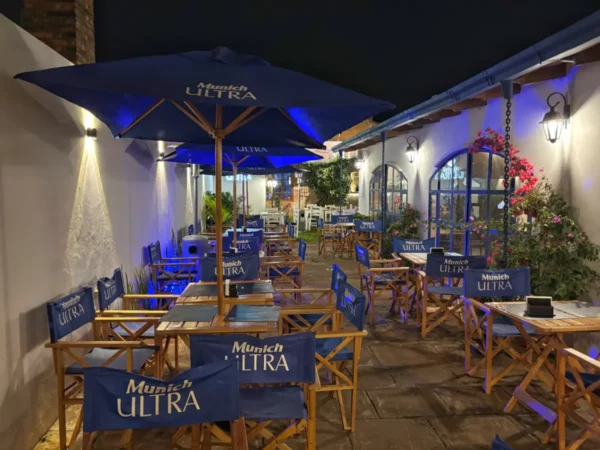 Outdoor dining area with blue umbrellas and wooden chairs, creating a cozy atmosphere in Villarica, Paraguay at night.