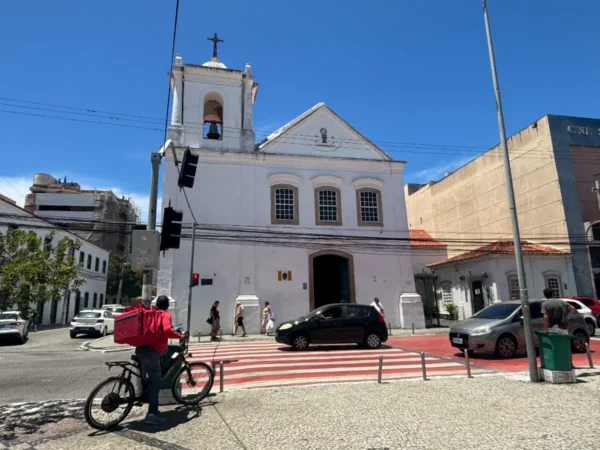 Cabo Frio features a white colonial church with a bell tower, surrounded by streets and pedestrians, in Rio de Janeiro, Brazil.