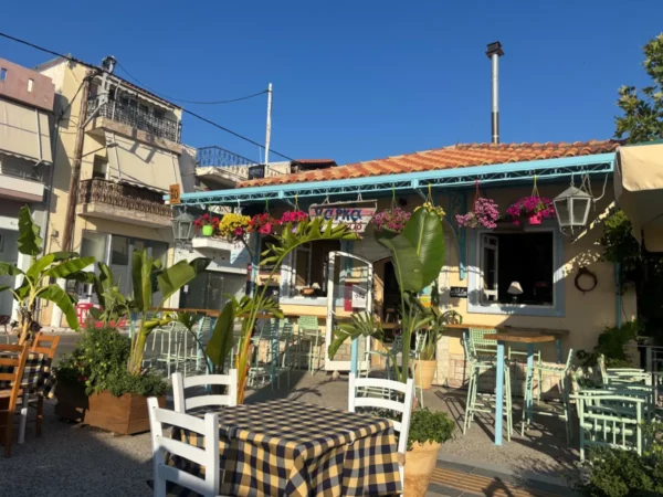 Charming tavern with blue and white decor, vibrant flowers, and checkered tables, nestled in Amarynthos, Euboea, Greece.