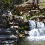 girl standing on rock beside a waterfall in the dimosaris gorge in south evia