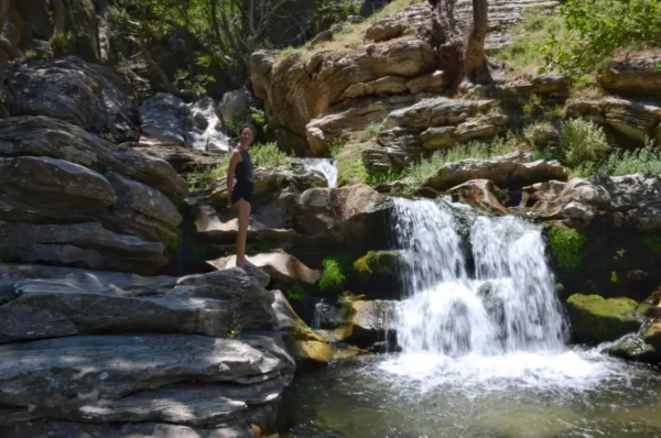 girl standing on rock beside a waterfall in the dimosaris gorge in south evia