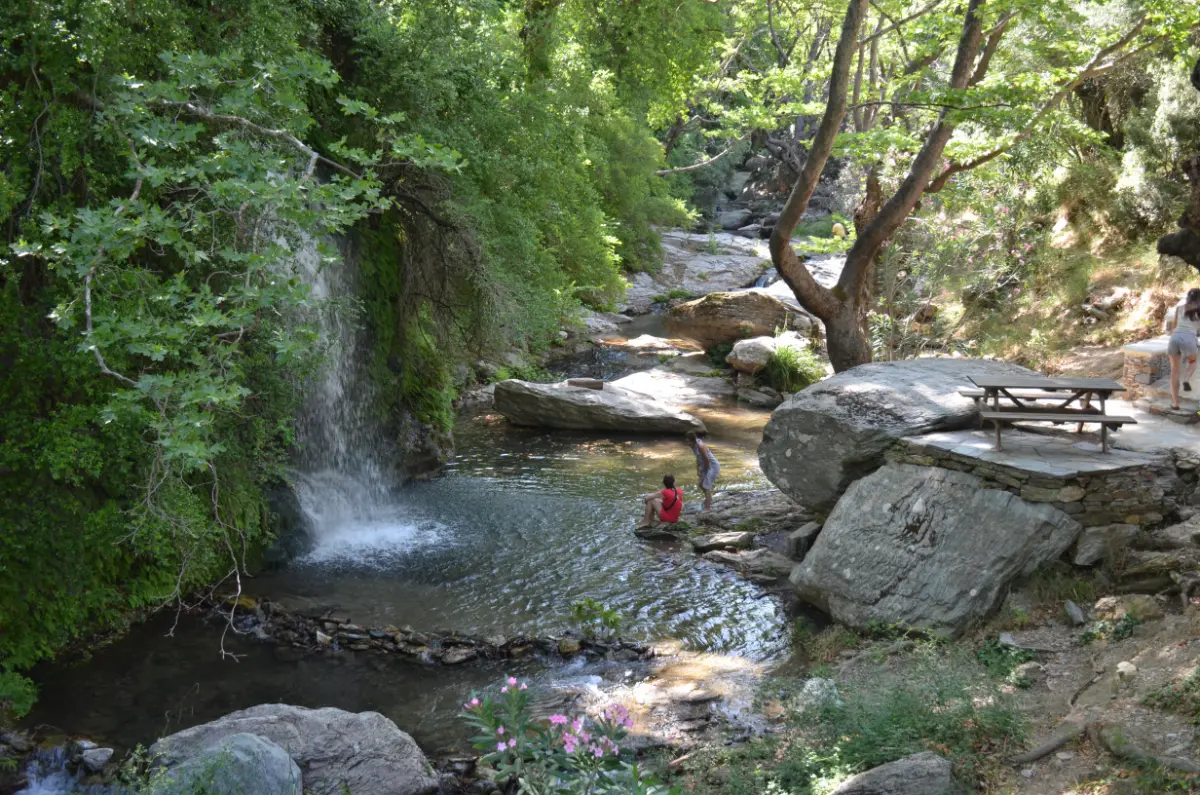 women sitting below the waterfall of platanistos on evia island