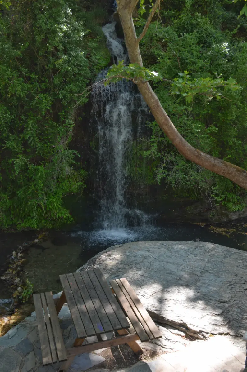 A nice spot for a picnic with wooden bench in front of waterfall on evia island in greece