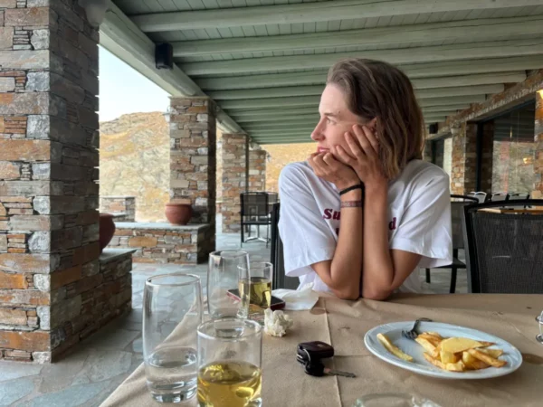 Relaxing at a seaside table with drinks and a plate of fries, overlooking the rocky landscape of Potami Beach, Euboea, Greece.