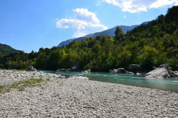 Clear blue waters of the Arachthos River flow through lush greenery and rocky banks near Ioannina, Greece.