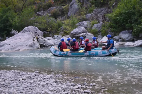 Rafting team navigates the turquoise Arachthos River, surrounded by lush greenery and rocky banks in Ioannina, Greece.