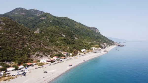 Chiliadou Beach features a sandy shoreline, clear turquoise waters, and lush hills on Euboea, Greece.