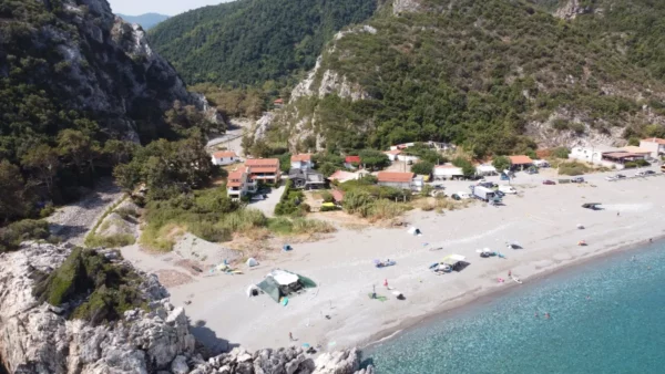Chiliadou Beach features a serene shoreline with clear blue water, sandy stretch, and green hills in Euboea, Greece.