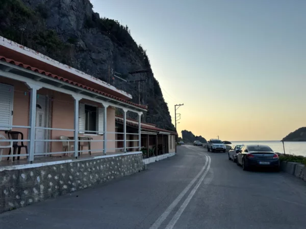 Chiliadou beach features quaint seaside cottages and parked cars along a winding road, overlooking the calm waters of Euboea, Greece.