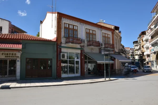 Charming street scene in Florina, Greece, showcasing colorful buildings with balconies and sunny blue skies.