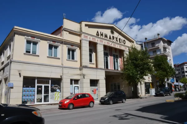 Colorful buildings line the street in Grevena, Greece, featuring the prominent Town Hall with its decorative facade.