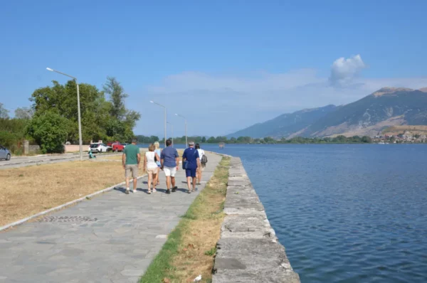 Relaxing stroll along the waterfront in Ioannina, Greece, with friends enjoying a sunny day by the tranquil lake.
