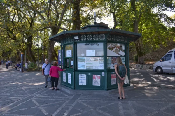 Quaint kiosk in Ioannina, Greece, surrounded by lush trees and visitors enjoying the pleasant atmosphere.