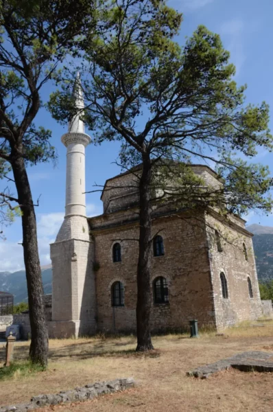 Historic mosque with a minaret surrounded by trees, showcasing the unique architecture of Ioannina, Greece.