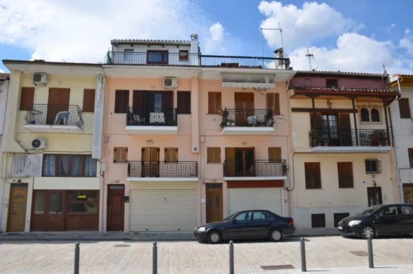 Charming residential buildings in Ioannina, Greece, showcasing pastel colors and balconies under a bright blue sky.