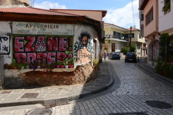 Colorful graffiti adorns a building near a cobblestone street in Ioannina, Greece, highlighting local art and charm.