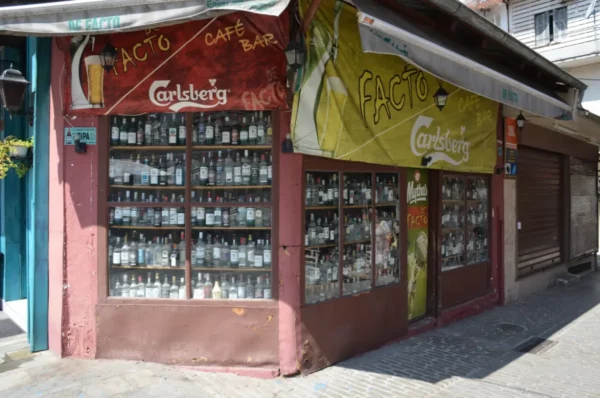 Colorful café bar facade featuring numerous glass bottles, located in Ioannina City, Greece.