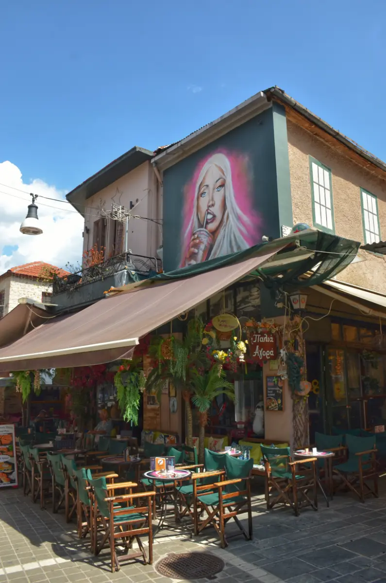street café in Ioannina with outdoor tables and a large wall mural of a woman, Greece