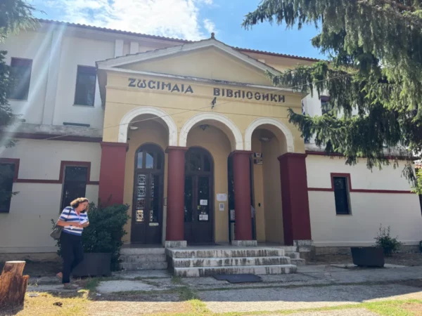 Zosimea Library showcases classic architecture with a striped awning and a person standing by the entrance in Ioannina, Greece.