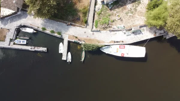 Boats lined up along the dock with calm waters reflecting the greenery in Ioannina, Greece.