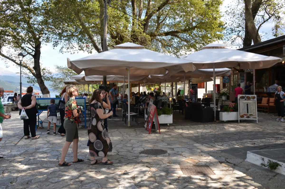 lakeside tavernas and café terraces on Ioannina Island, with people dining under plane trees by Lake Pamvotida, Greece