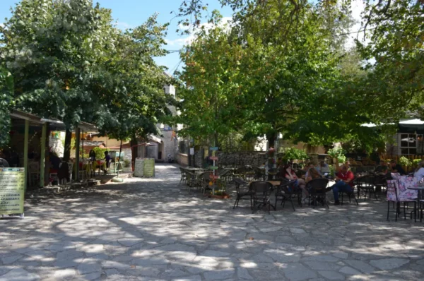 Charming café scene with shaded outdoor seating under leafy trees in Ioannina, Greece, inviting relaxation and conversation.