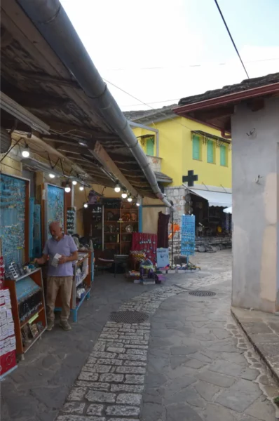 Charming streets of Ioannina Island, Greece, featuring colorful shops, cobblestone paths, and a local vendor.