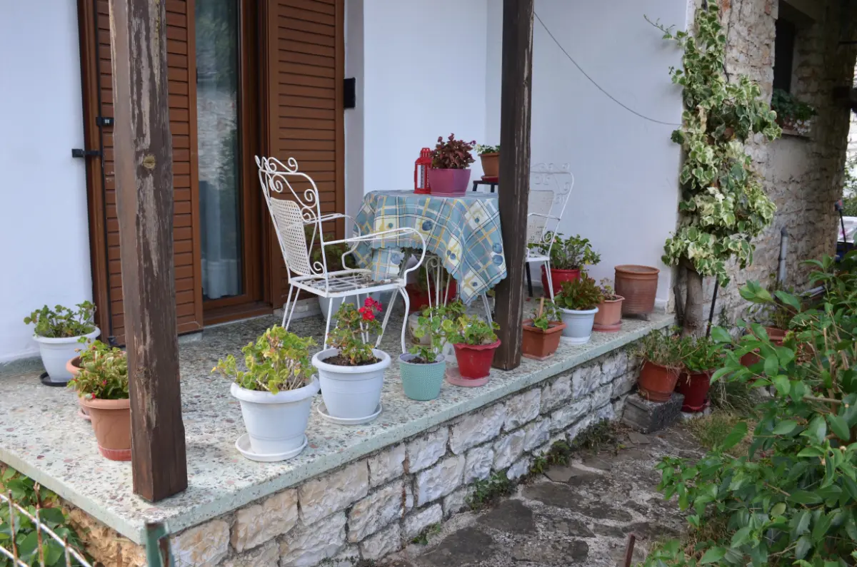 Cute llittle porch with small table and plant pots in front of a house on ioannina island